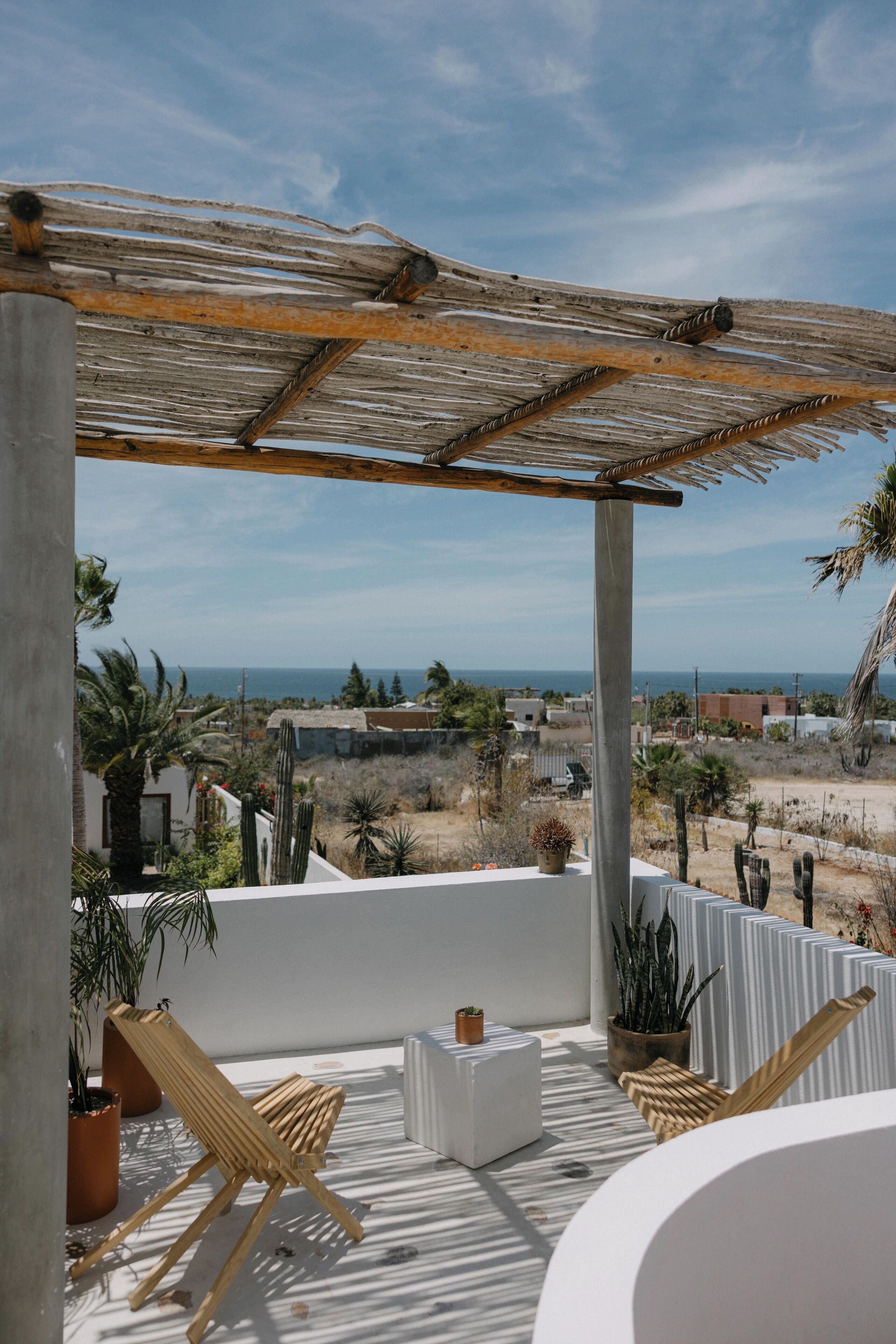 Ein Balkon mit Meerblick, ein Holzstuhl, ein kleiner Tisch und Kübelpflanzen.