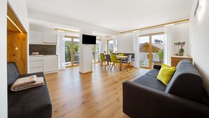 Un espacio habitable moderno con sofá, comedor y cocina.