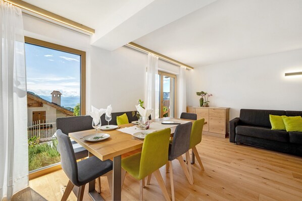 A dining area with a wooden table, chairs, and a view of a mountain.