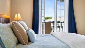 A hotel room with a bed, a nightstand with a lamp, and a view of the outside balcony. - MarcoWaterfront-BalconyViews-Pool+Spa-Fishing (Marco Island)