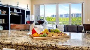 A kitchen counter with a cheese board, fruits, and wine glasses. - MarcoWaterfront-BalconyViews-Pool+Spa-Fishing (Marco Island)