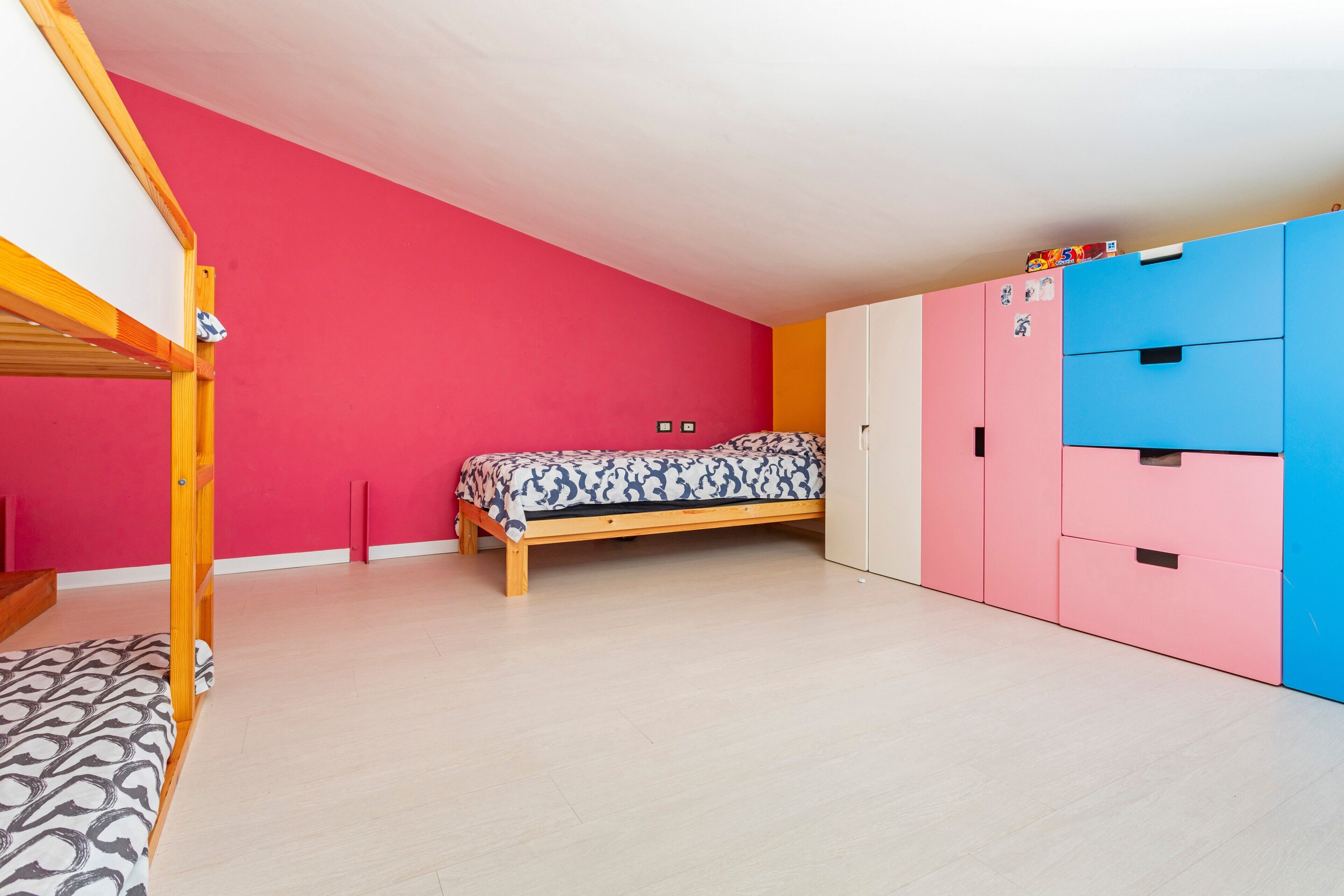 Ein Zimmer mit Etagenbett, einem Einzelbett, einem Kleiderschrank und einer Kommode.
