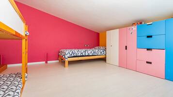 Ein Zimmer mit Etagenbett, einem Einzelbett, einem Kleiderschrank und einer Kommode.