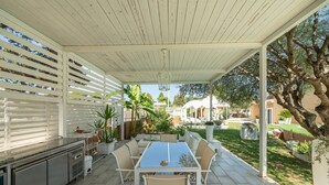 An outdoor patio with a dining table and chairs, a grill, and potted plants. - Holiday Home 'Villa Leon with Private Pool' with Sea View, Wi-Fi and Air Conditioning (Quartu Sant'Elena)