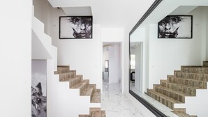 A modern staircase with wooden steps and white walls, leading to a hallway with a glass door. - Holiday Home 'Villa Leon with Private Pool' with Sea View, Wi-Fi and Air Conditioning (Quartu Sant'Elena)