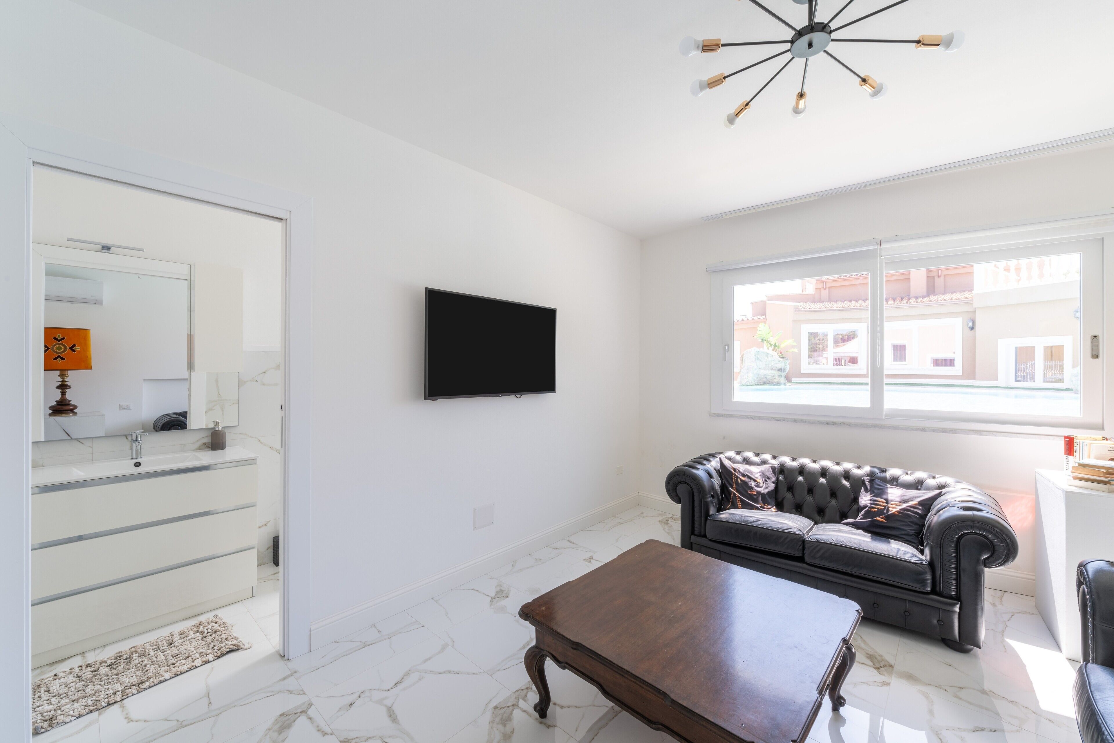 A living room with a sofa, a coffee table, a TV, and a window with a view.