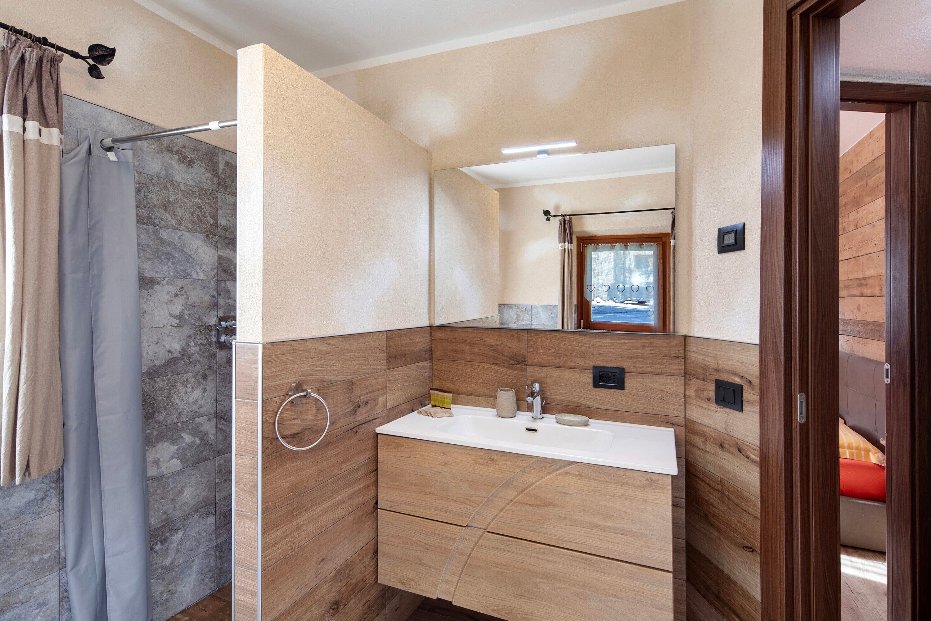 Ein Badezimmer mit Dusche, Waschbecken und Spiegel.