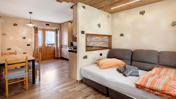 Una habitación con una mesa de comedor de madera, sillas, un sofá y una cama.