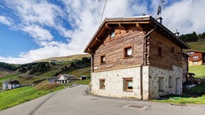 Una cabaña de madera con base de piedra, techo inclinado y un pequeño porche.