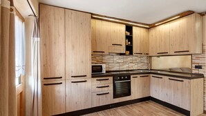 Una cocina moderna con armarios de madera, microondas, horno y lavaplatos.