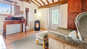 Una habitación acogedora con chimenea, vigas de madera, un escritorio y una silla cómoda.