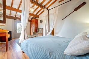 Une chambre à coucher avec un lit, des poutres en bois au plafond, une chaise, un bureau et une cheminée.