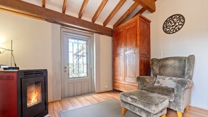 Una habitación con un estufa de leña, un armario de madera, un sillón gris y un adorno mural estampado.