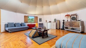 A spacious living room with a sofa, a dining table, and a bed.