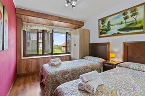 Habitación de hotel con dos camas, un cuadro, una ventana con cortinas y vista a un edificio.
