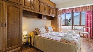 Une chambre avec un grand lit, une armoire en bois et une fenêtre avec des rideaux.