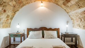 Ein Zimmer mit einem Bett, zwei Nachttischen und einem Bogen in der Steinwand.