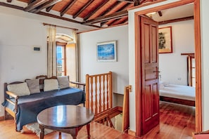 Une pièce comprenant un lit, une chaise en bois, une table et un tableau accroché au mur.