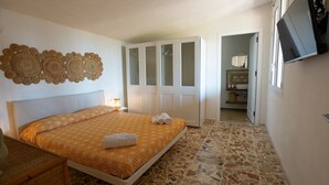 A bedroom with a bed, a wardrobe, a television, and a mosaic floor. - Holiday Home 'Suite La Barracca' with Sea View, Wi-Fi and Air Conditioning (Marsala)