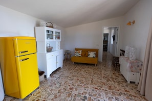 A kitchen with a yellow refrigerator, white cabinets, a yellow sofa, and a patterned floor. - Holiday Home 'Suite La Barracca' with Sea View, Wi-Fi and Air Conditioning (Marsala)