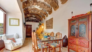 A dining area with a glass table, wooden chairs, a decorative cabinet, and a stone ceiling. - Vacation Home 'Palacio Taro Chimida' with Private Pool (Teguise)