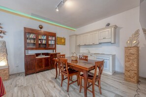 Un coin repas avec une table et des chaises en bois, une bibliothèque et des meubles blancs.