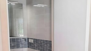 Un baño con una puerta blanca, un espejo, un lavabo y un perchero para toallas.