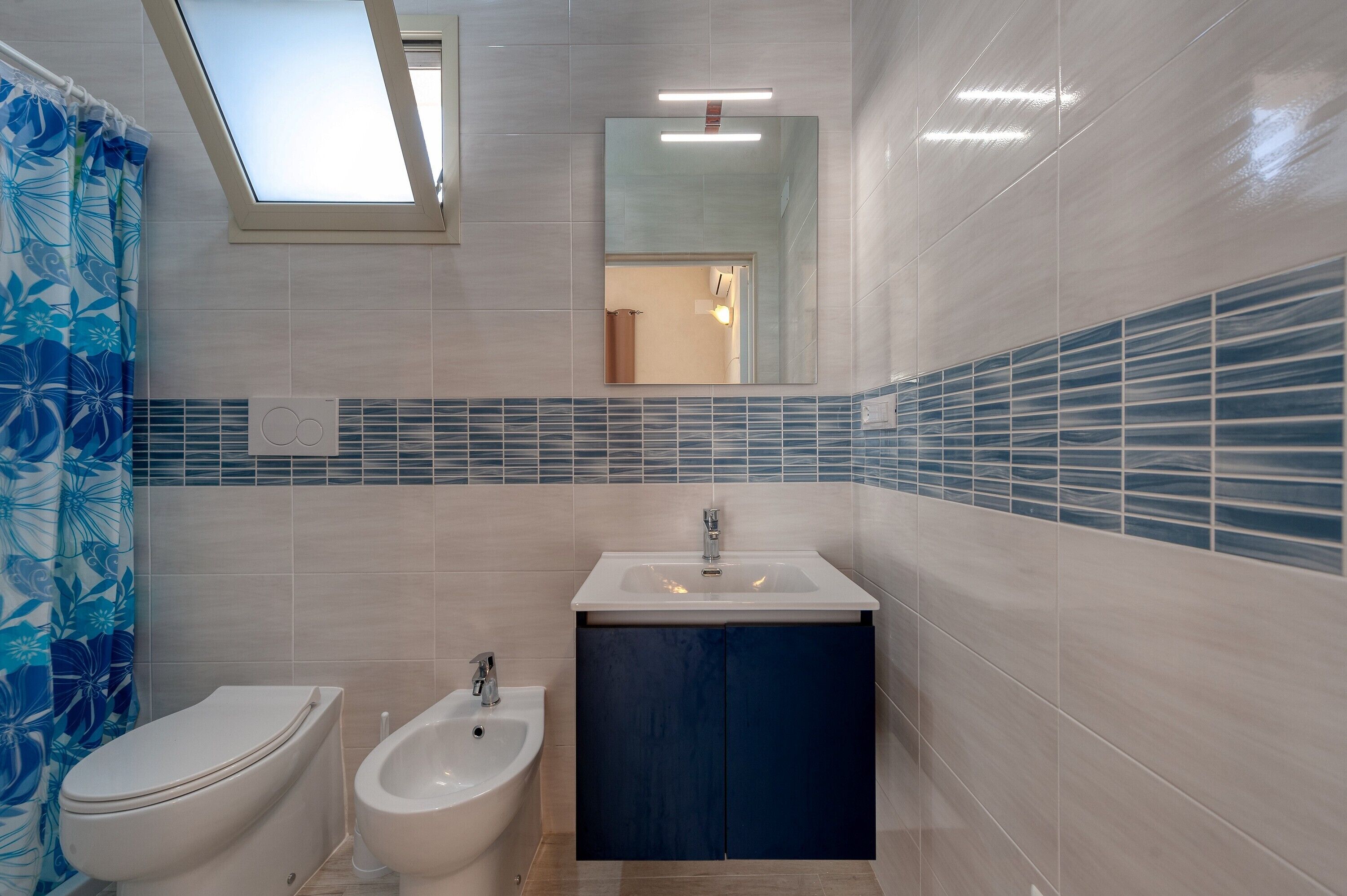 Ein Badezimmer mit Toilette, Bidet, Waschbecken und einem Oberlicht.