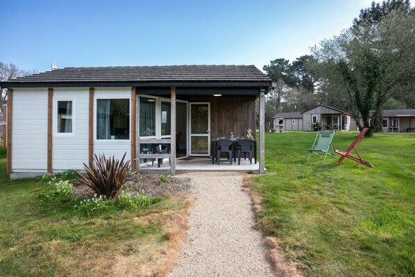 A small, single-story building with a covered porch, a gravel path leading to the entrance, and a grassy yard.
