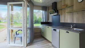 A modern kitchen with a built-in dishwasher, a sink, and a window with curtains.
