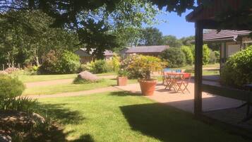 Ein gepflegter Garten mit Terrasse, Pool und überdachter Sitzecke.