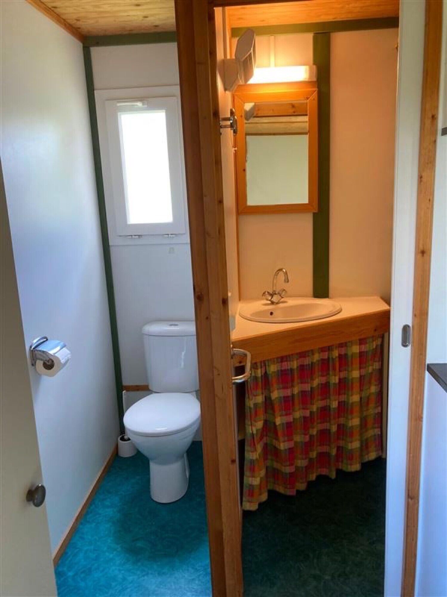 Ein kleines Badezimmer mit Toilette, Waschbecken und Fenster.