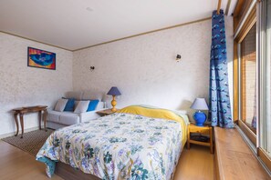 Une chambre à coucher avec un lit, des tables de chevet, une lampe, un tableau et une fenêtre avec des rideaux.