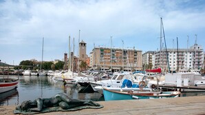 Ein Yachthafen mit vor Anker liegenden Booten, einer Statue und Gebäuden im Hintergrund.