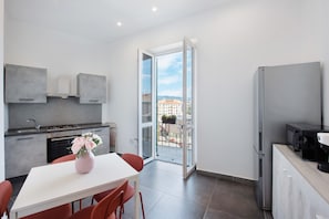 Una cocina moderna con comedor, un refrigerador y vistas a edificios a través de un ventanal.