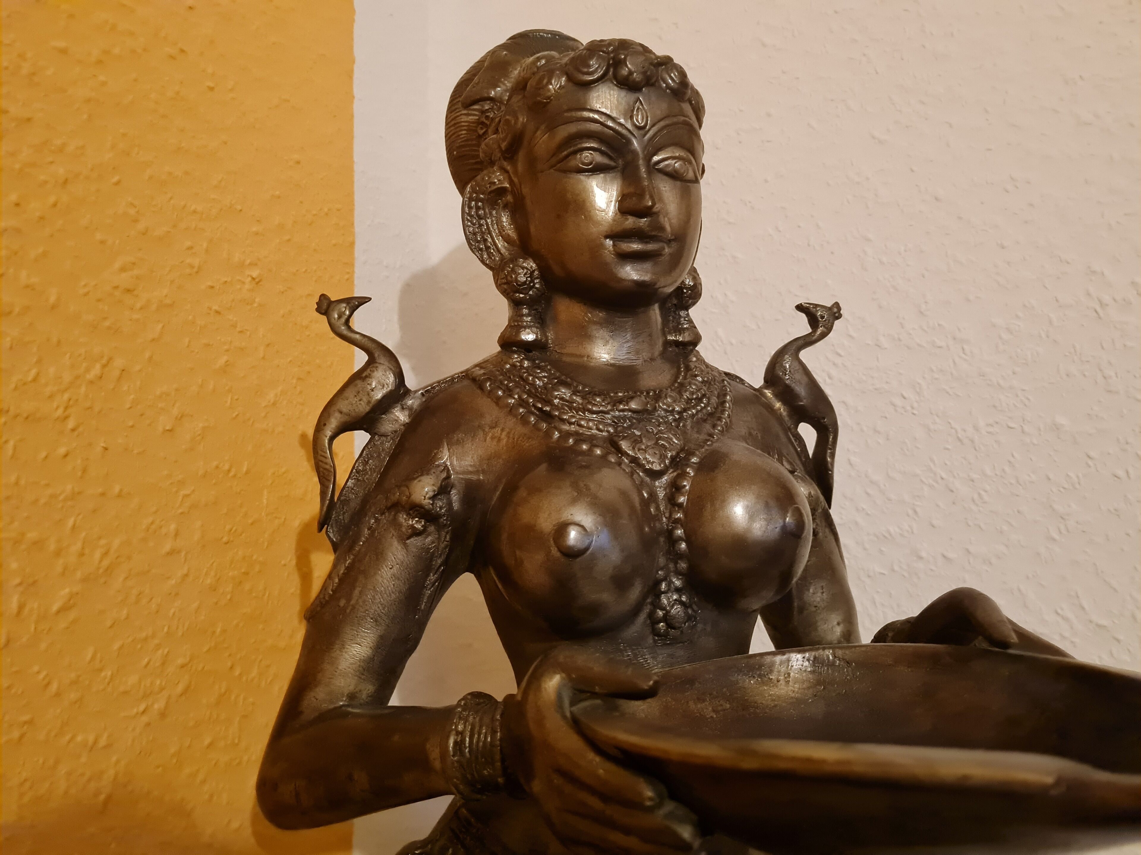 En staty som föreställer en gudom och som håller i en skål.