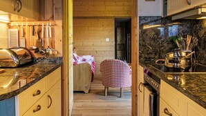A narrow kitchen with wooden cabinets, a granite countertop, and a dining area with a checkered tablecloth. - Mirabeau 6 by Interhome (Nendaz)