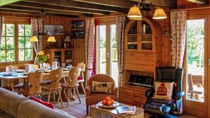 A cozy cabin interior with a dining area, a living room with a sofa and armchairs, and a fireplace. - Mirabeau 6 by Interhome (Nendaz)