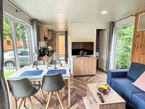 Un salon moderne et bien éclairé, comprenant une table à manger, des chaises, un canapé et un téléviseur.