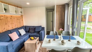 A modern living room with a blue sofa, a wooden coffee table, and a glass dining table with blue placemats.