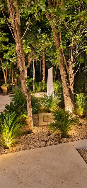 A landscaped garden with trees, shrubs, and a paved walkway.