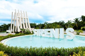 A pool area with large white letters spelling "SIRENIS" and a modern white structure in the background.