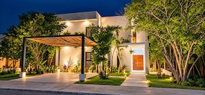 A modern building with a covered entrance and a well-lit garden area. - Villa Alexa: Experience the Adventure! (Akumal)