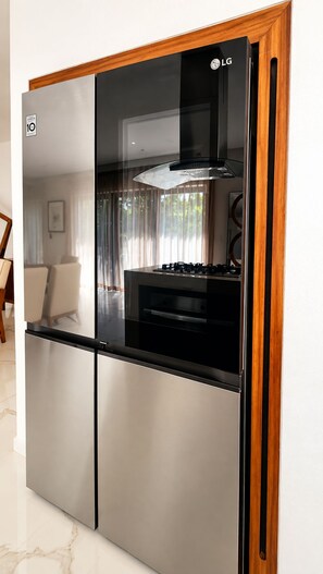 A modern kitchen with a stainless steel refrigerator, a built-in oven, and a gas stove.