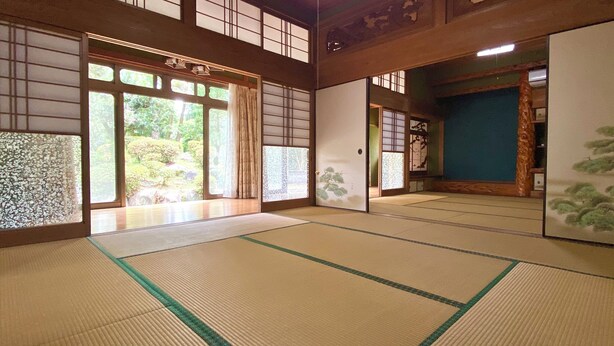 Ein traditioneller japanischer Raum mit Tatami-Böden, Schiebetüren und Blick auf einen Garten.