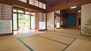 Una habitación tradicional japonesa con suelo de tatami, puertas correderas y vistas a un jardín.