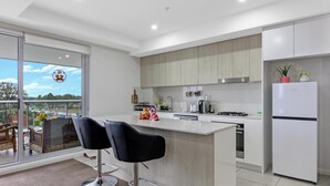 Une cuisine moderne dotée d’un grand îlot central, de tabourets de bar et d’un réfrigérateur.