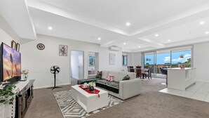 Un salon moderne avec un canapé, un téléviseur et un coin repas équipé de chaises.