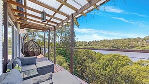 Uma área de estar coberta ao ar livre, com vista para uma ponte e vegetação.
