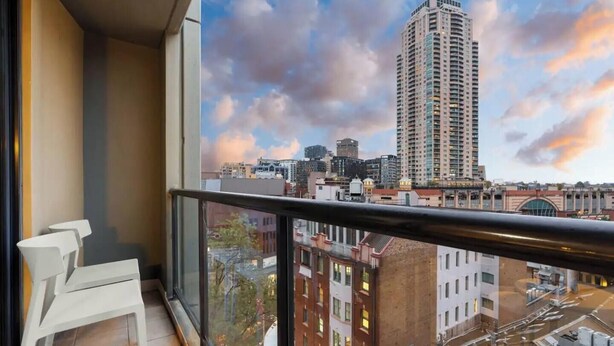 A balcony with a city view, a railing, and a chair.